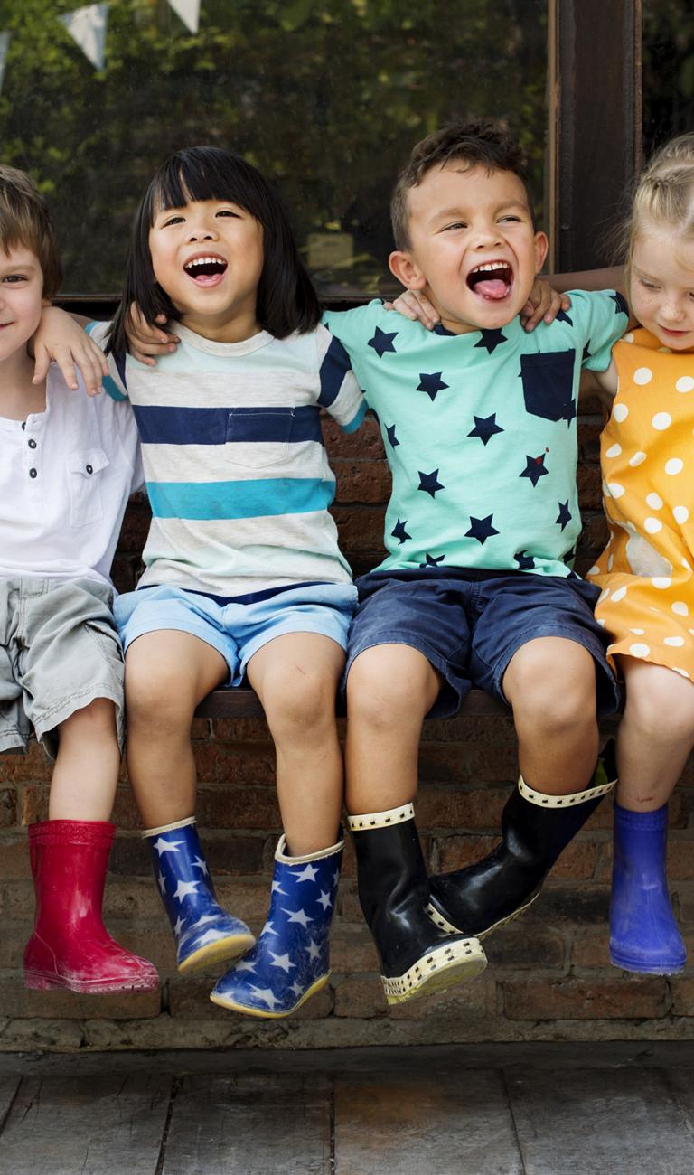 Image of six children sitting on a bench laughing